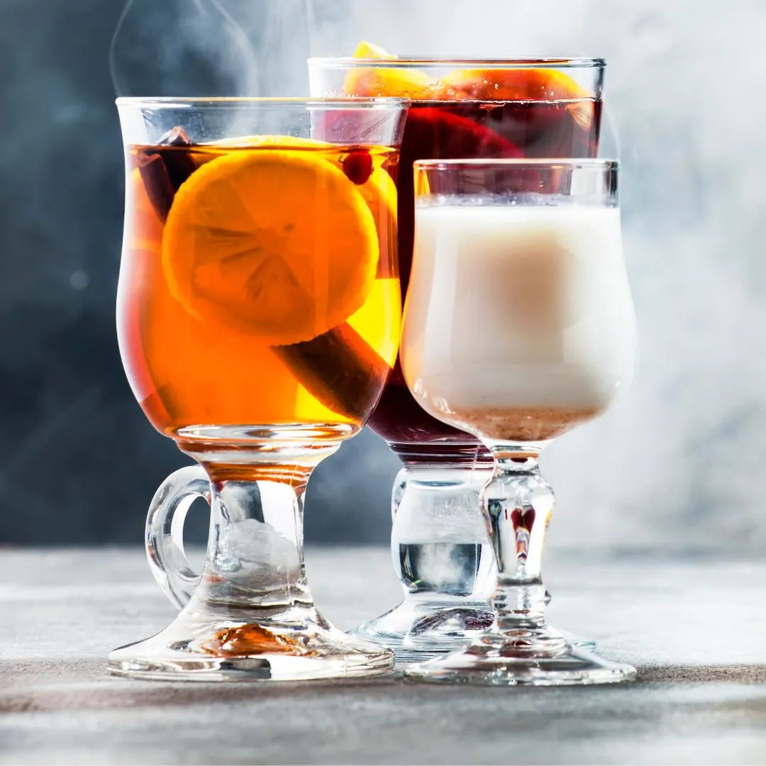 Ein dampfender Punsch in einer Tasse mit Orangen- und Zimtstangen-Garnitur