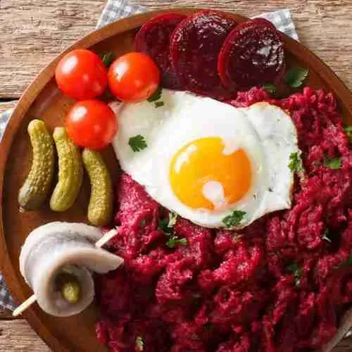 Ein detailreiches Bild des Labskaus mit Beilagen auf einem rustikalen Teller