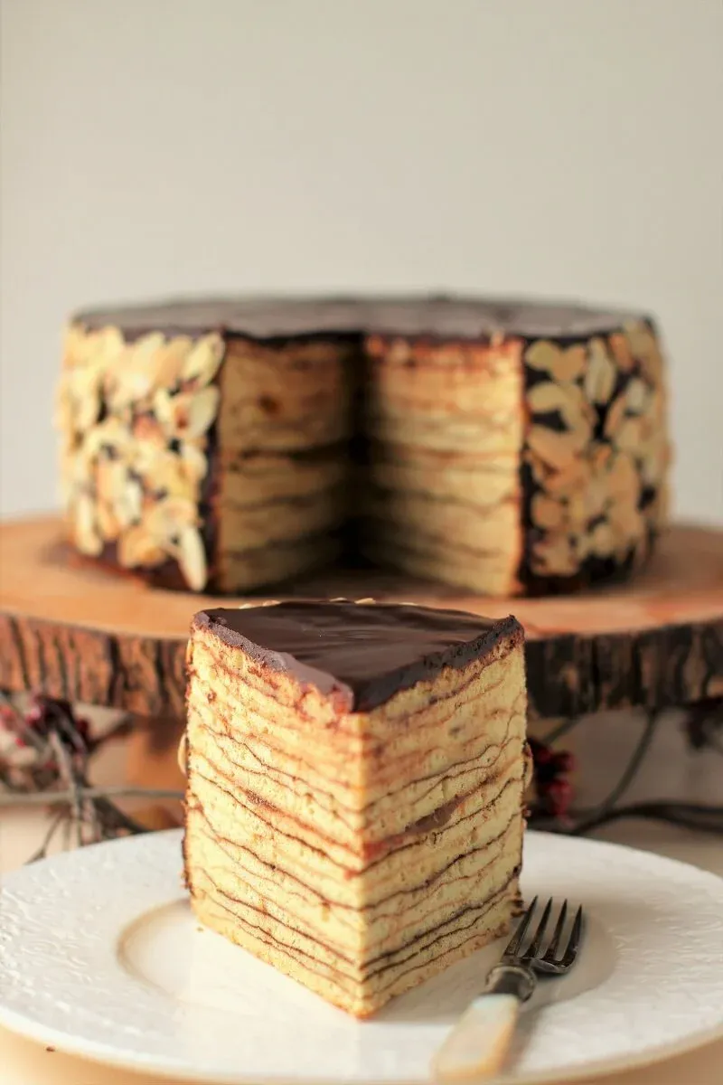 Ein elegantes Stück Baumkuchen vor dem ganzen Kuchen auf einem Ständer