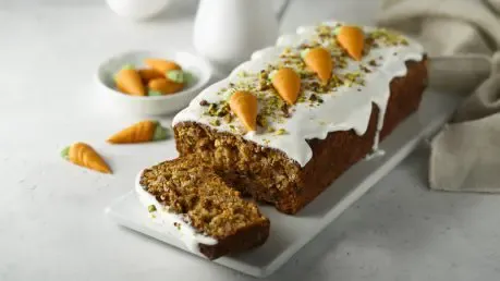 Ein frisch gebackener Karottenkuchen mit Zuckerguss und kleinen Marzipankarotten