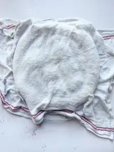 Ein frisch gebackenes Fladenbrot, das mit einem feuchten Geschirrtuch bedeckt ist, um es weich zu halten