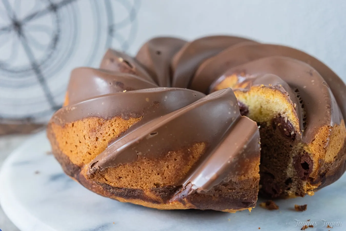 Ein frischer Marmorkuchen mit Kirschen, angeschnitten, zeigt die saftige Textur und die glänzende Schokoglasur