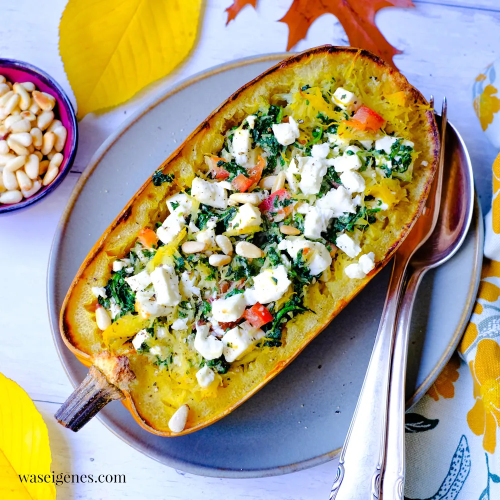 Ein gebackener Spaghettikürbis, gefüllt mit einer Spinat-Feta-Mischung, bereit für den Ofen