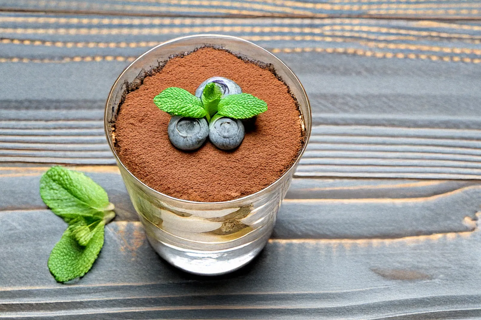Ein Glas mit Low-Carb-Tiramisu, bestreut mit einer feinen Schicht Kakaopulver