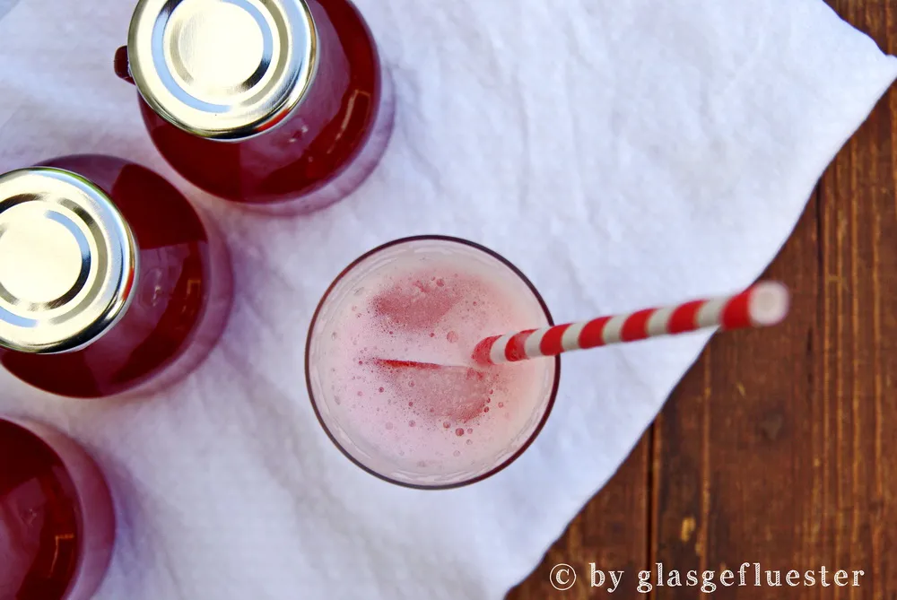 Ein Glas mit rotem Erdbeer-Rhabarber-Sirup