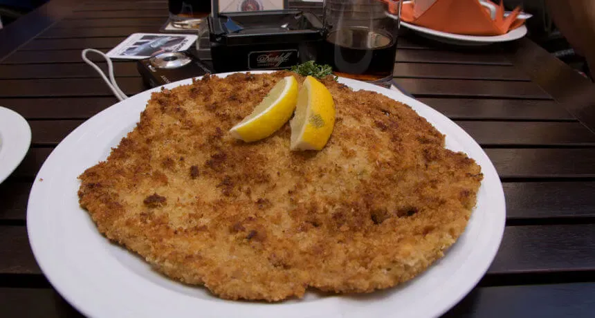 Ein knuspriges Wiener Schnitzel mit Zitronenspalte und Preiselbeeren.