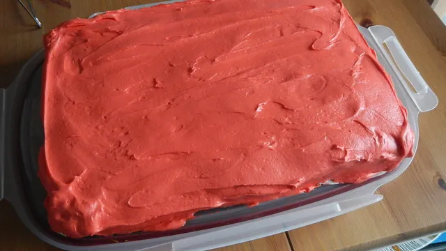 Ein Kuchen wird mit rotem Frosting bestrichen, als Basis für die Spider-Man Dekoration