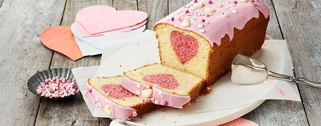 Ein liebevoll dekorierter Herzkuchen mit Beeren und Puderzucker