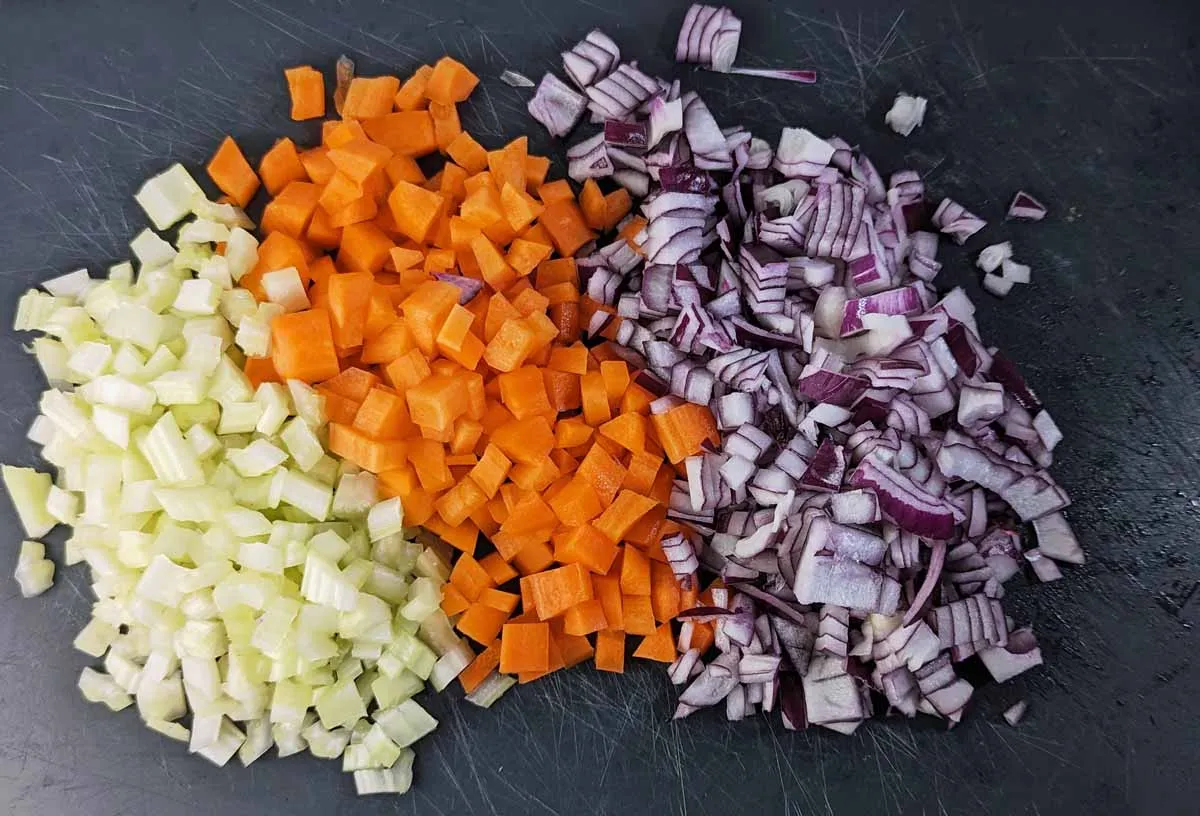 Ein Mirepoix aus fein gehackten Karotten, Sellerie und roten Zwiebeln