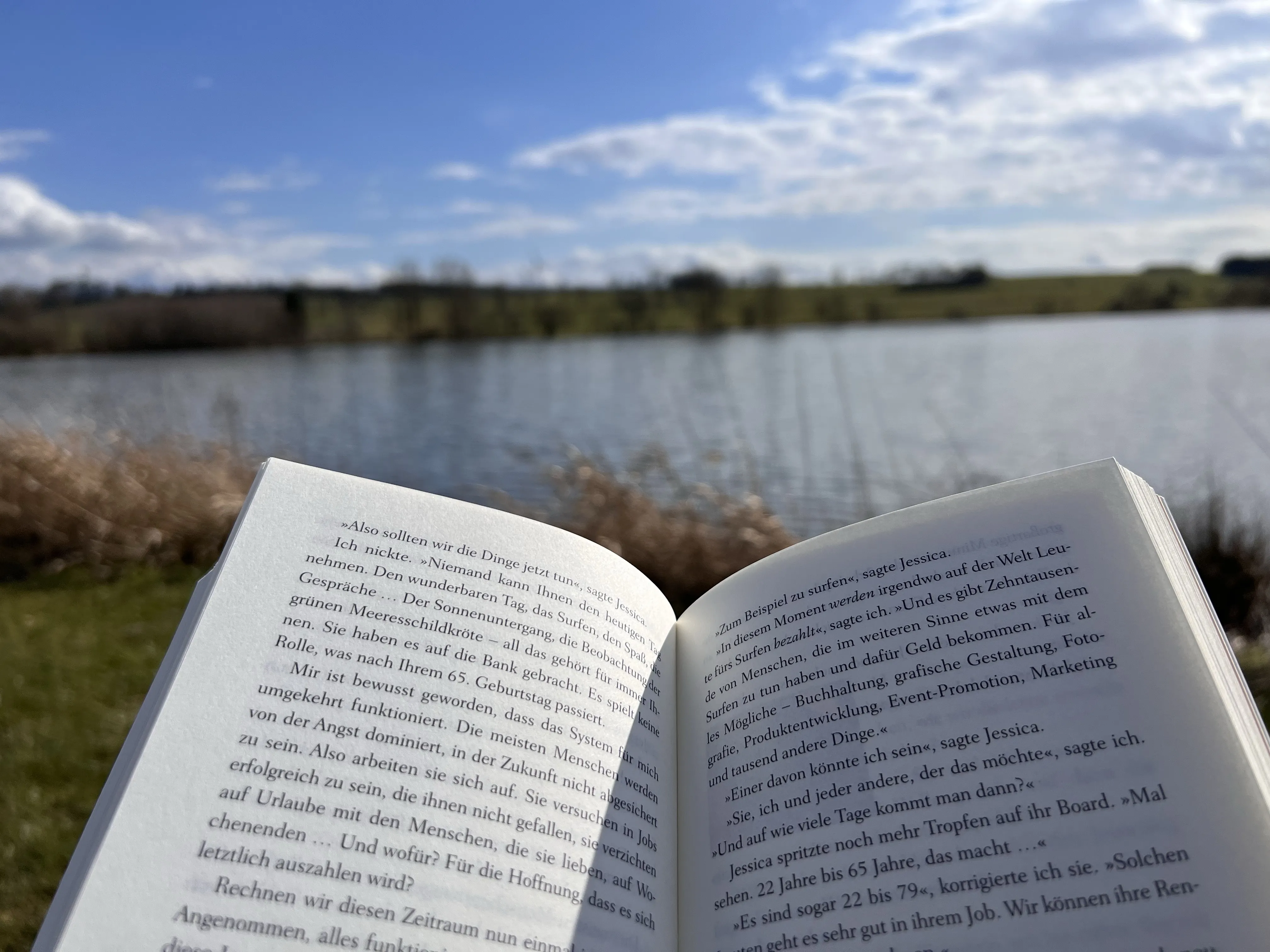 Ein offenes Buch mit dem Titel "Das Café am Rande der Welt" liegt auf einem Tisch