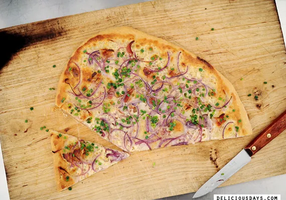 Ein reich gedeckter Tisch mit verschiedenen Brotsorten, Käse, Wurst und Flammkuchen