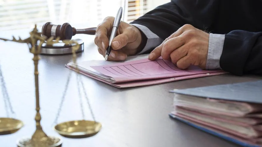 Ein Richter unterzeichnet ein wichtiges Urteil, das die Kürzung von Rentenfaktoren bei Riester-Verträgen betrifft.