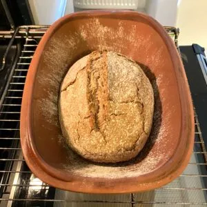 Ein Sauerteigbrot-Laib ruht im Römertopf, bereit zum Backen