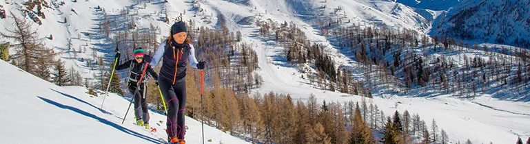 Ein Skifahrer gleitet eine verschneite Piste hinunter unter blauem Himmel