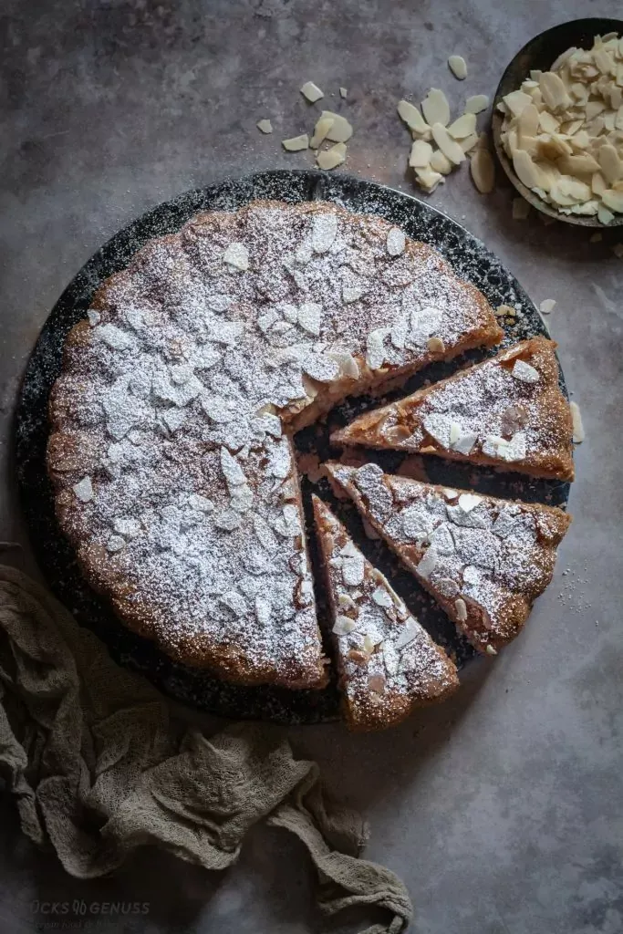 Ein Stück glutenfreier Apfelkuchen auf einem Teller, daneben eine Tasse Kaffee