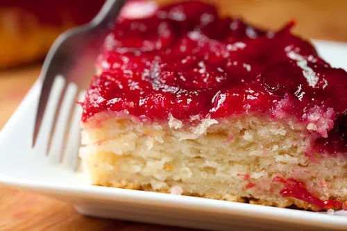 Ein Stück saftiger Pflaumenkuchen auf einem Teller, mit goldbraunem Hefeteig und reifen Pflaumen