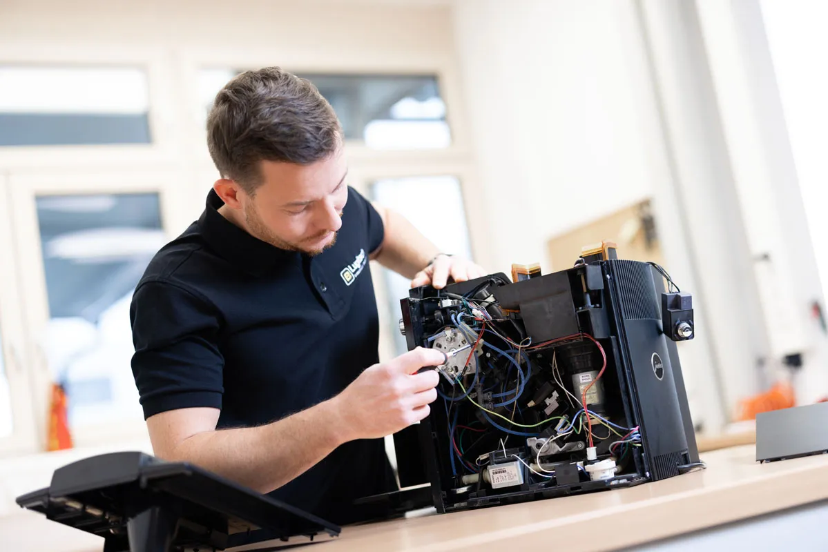 Ein Techniker repariert eine Kaffeemaschine mit Werkzeugen
