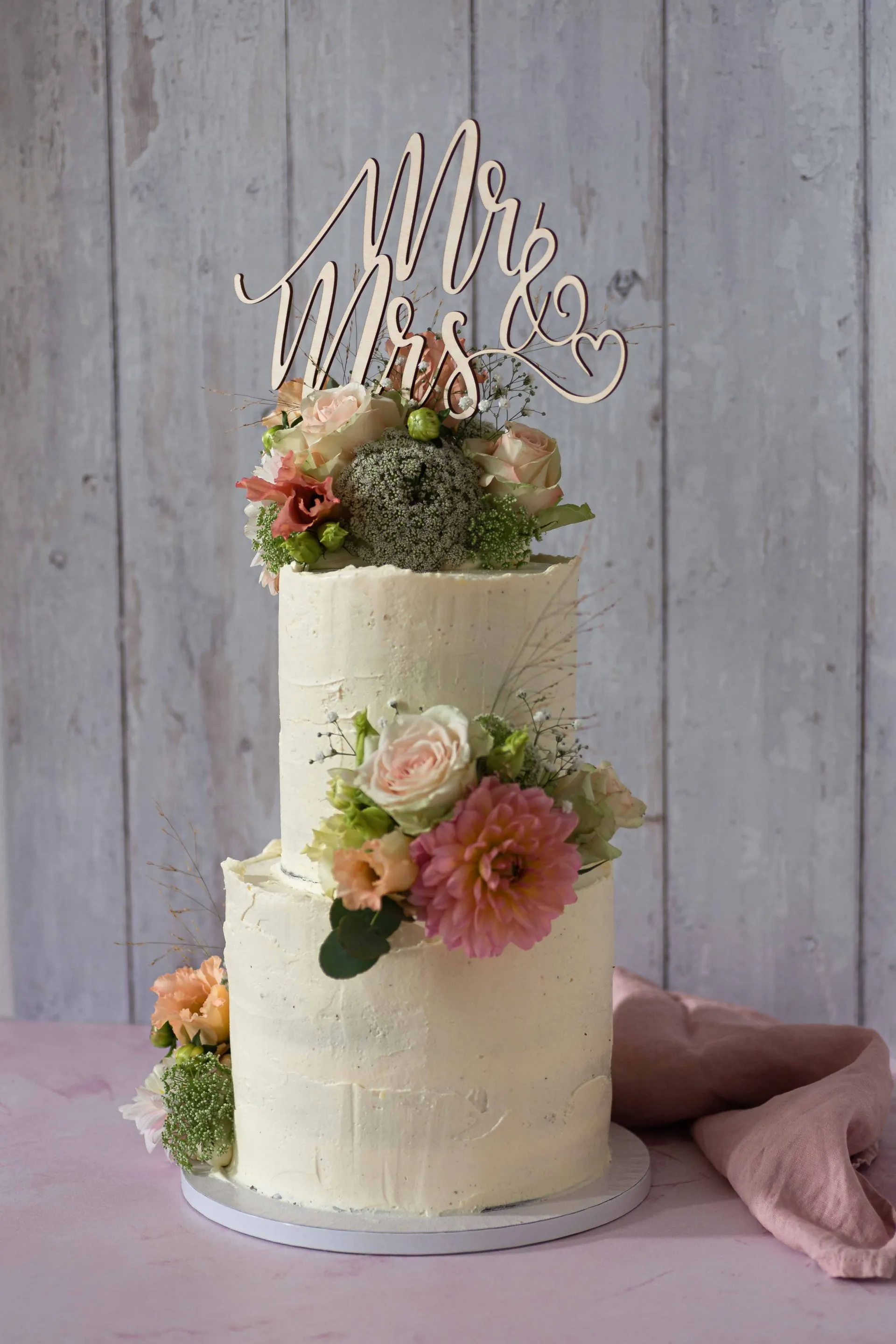 Eine dreistöckige Hochzeitstorte mit Blumen und Macarons