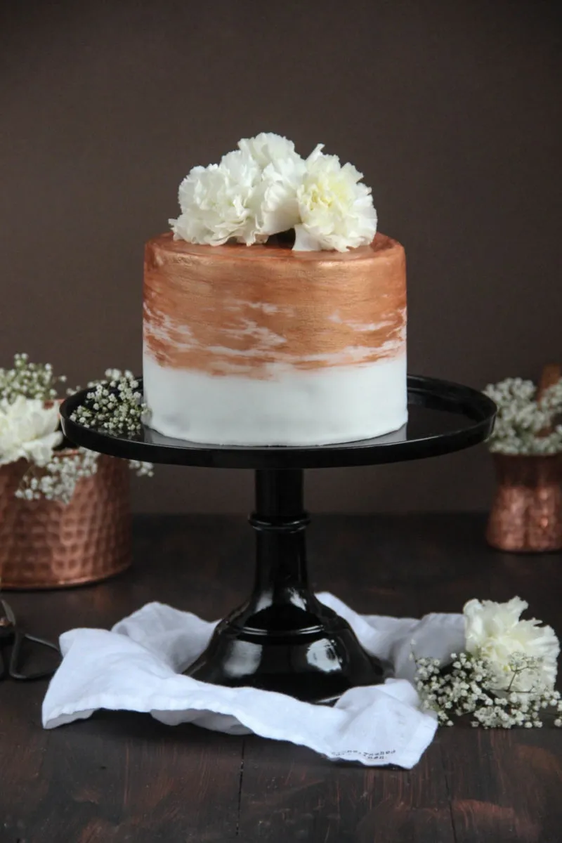 Eine elegante Nougat-Fondant-Torte mit weißem Überzug und Kupferakzenten