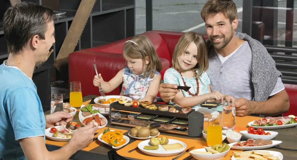 Eine Familie genießt gemeinsam einen gemütlichen Raclette-Abend