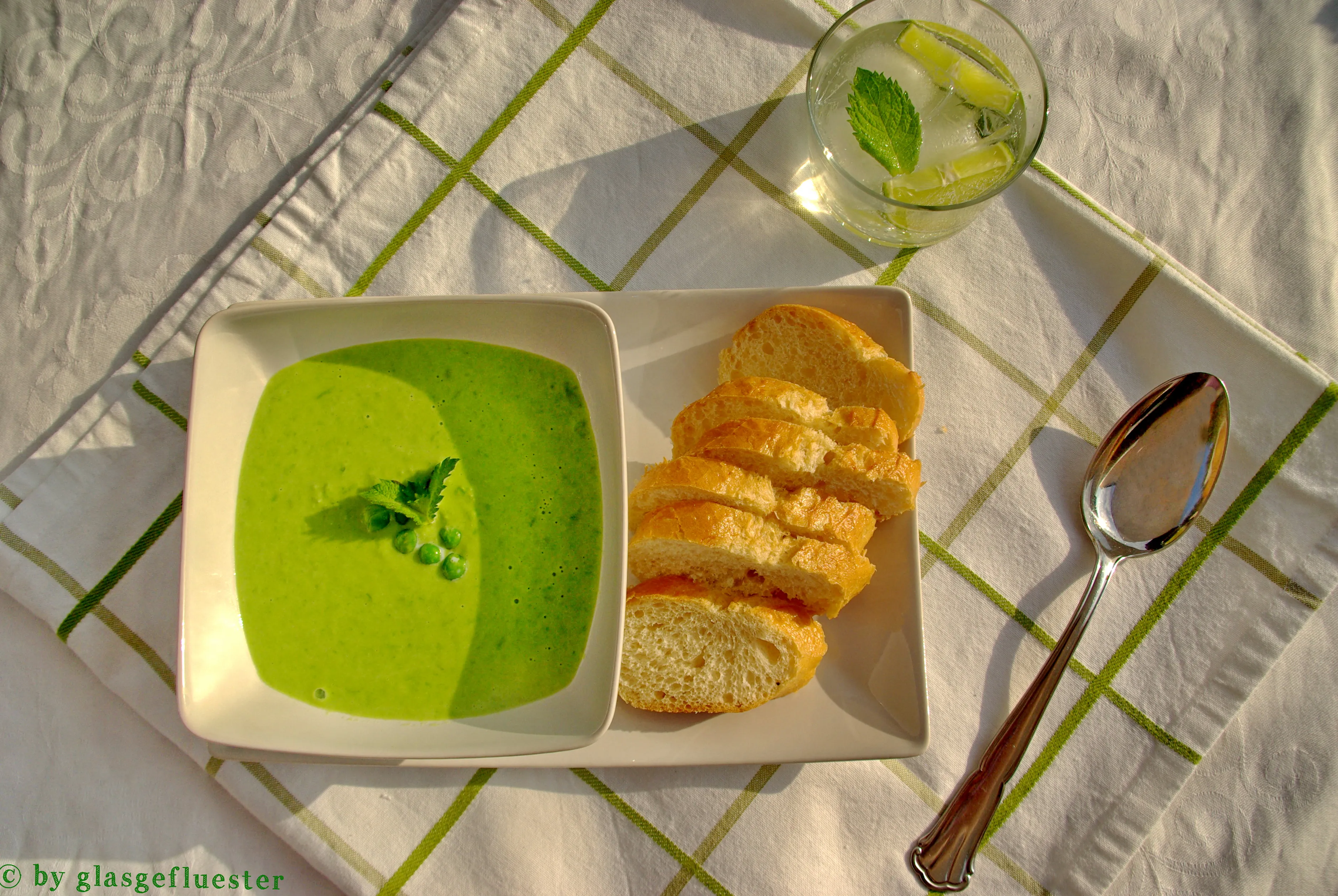 Eine grüne Erbsen-Minze-Cremesuppe in einer weißen Schale, garniert