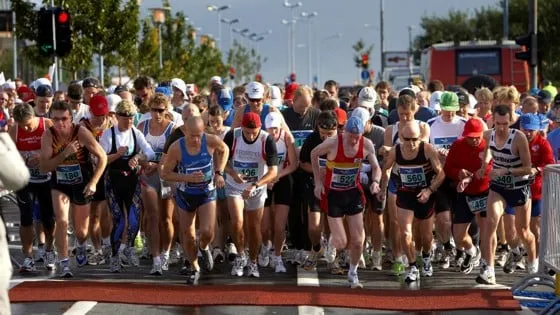 Eine Gruppe von Läufern beim Start eines Triathlons, die über eine Straße laufen.