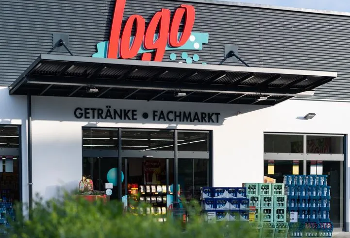 Eine Hand hält ein Smartphone mit der logo Getränke App im Getränkemarkt