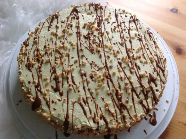Eine köstliche Low Carb Pistazien-Sahne-Torte mit Lebkuchenbiskuit auf einem Holzbrett