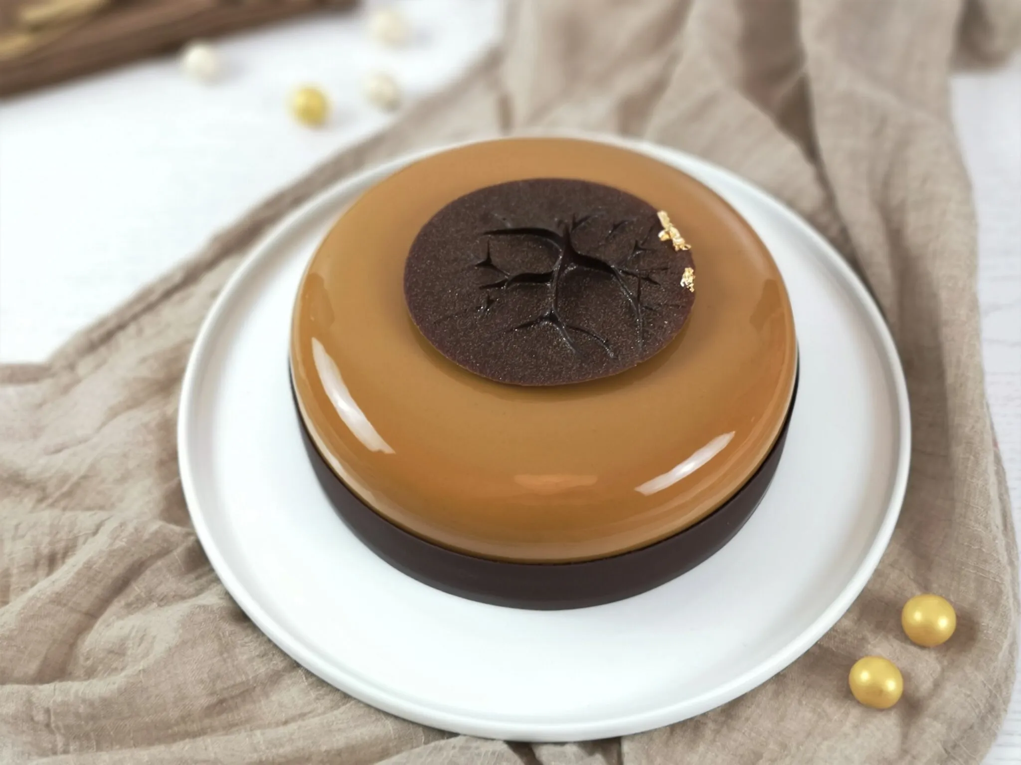 Eine kunstvoll dekorierte Torte mit goldener Glasur und Schokoladendekorationen auf einer festlich gedeckten Tafel