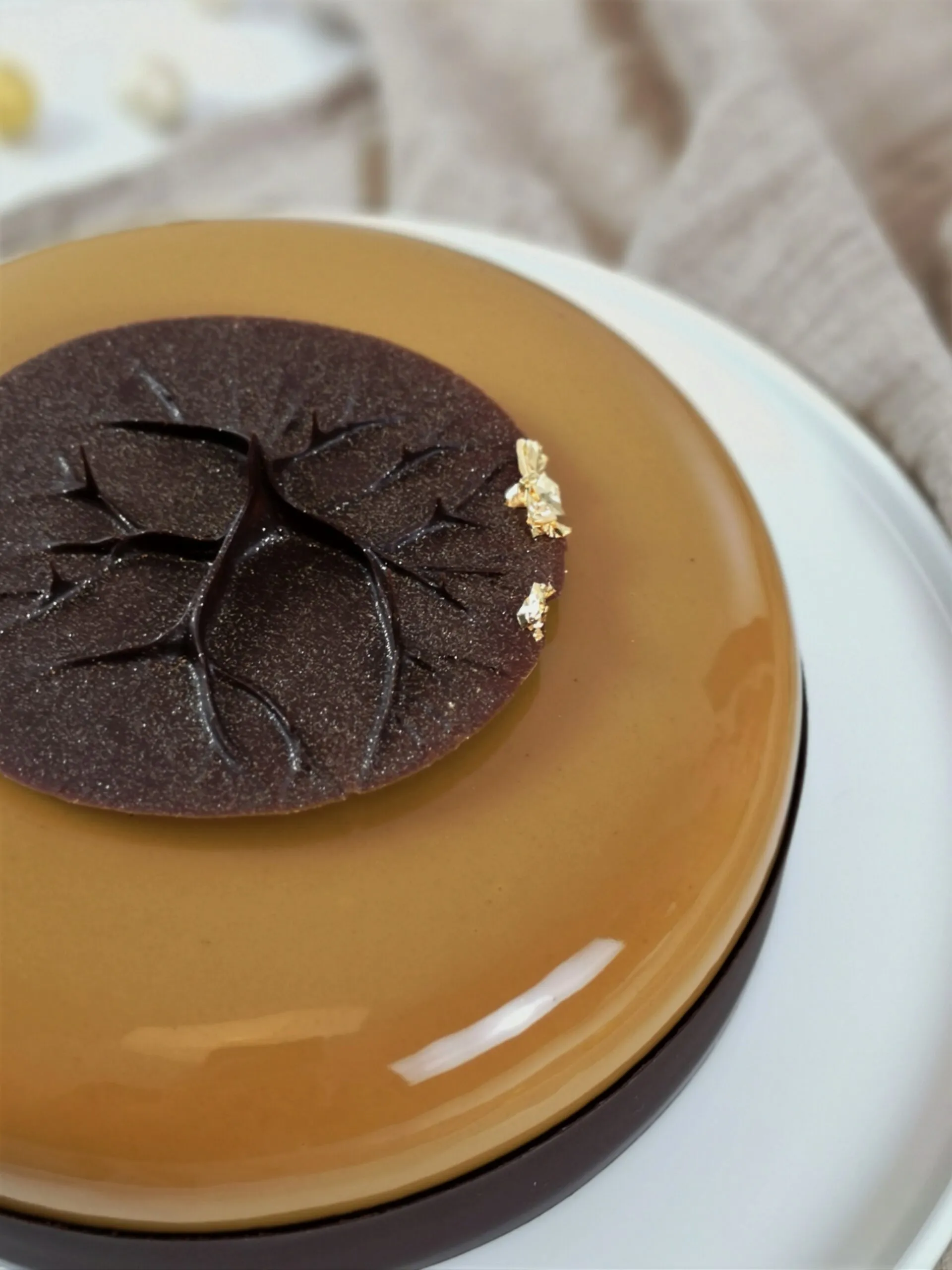 Eine mehrschichtige Torte, glasiert mit einer goldenen Mirrorglaze und verziert mit Schokoladenspiralen und -spitzen