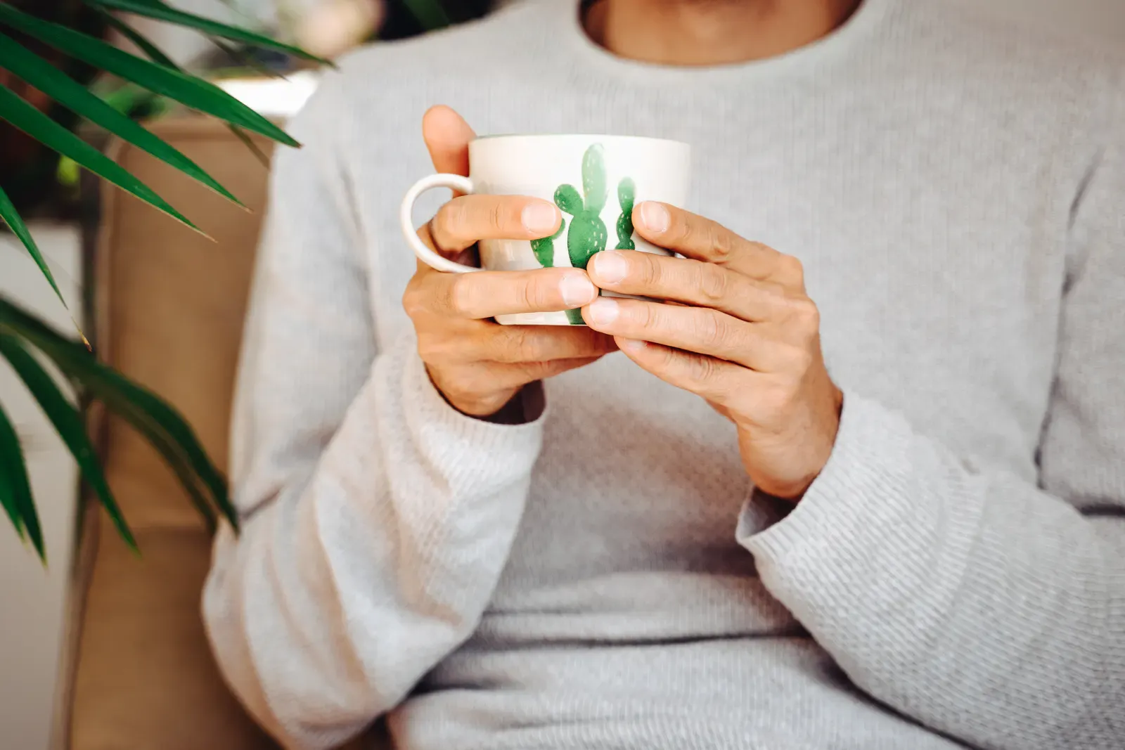 Eine Person trinkt entspannt eine Tasse Kaffee zu Hause