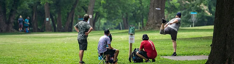 Eine Person wirft eine Disc-Golf-Scheibe auf einem Parcours