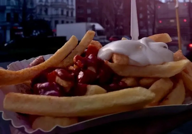 Eine Portion Currywurst mit Pommes und reichlich Sauce.