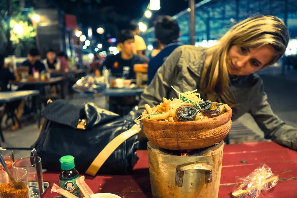 Eine Reisende betrachtet schwarze, geleeartige Eier in Suppe