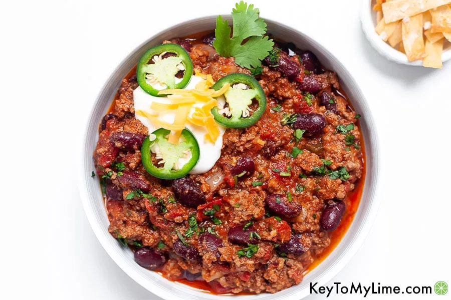 Eine Schale Chili con Carne neben einer Schale gebratener Tortillastreifen