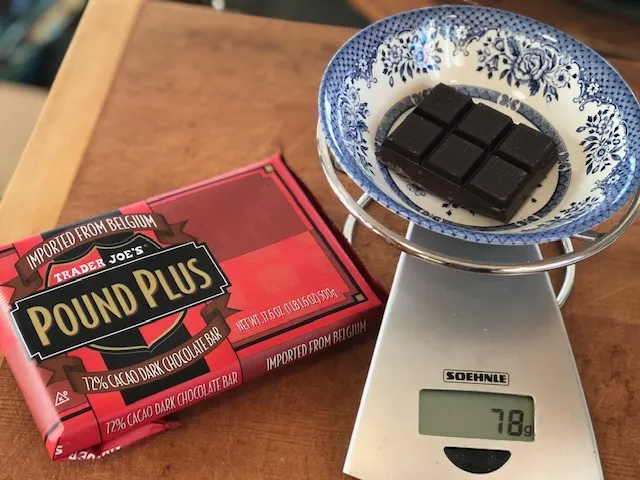 Eine Tafel dunkler Schokolade liegt auf einer Schneidefläche.