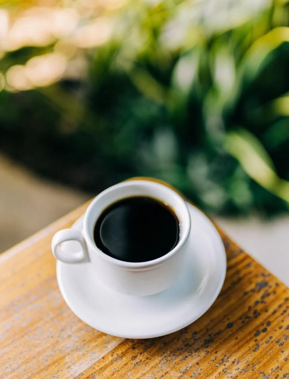 Eine Tasse Filterkaffee, frisch zubereitet, steht neben einer Filterkaffeemaschine