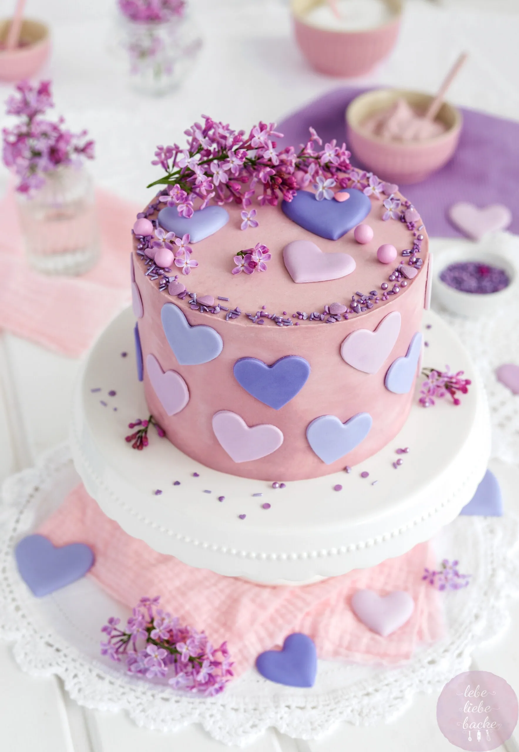 Eine wunderschön dekorierte Mandarinen Käsesahnetorte mit Fliederblüten und rosafarbenem Überzug