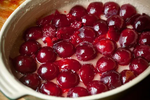 Eng aneinandergereihte Pflaumenhälften auf einem Zuckergrund in der Backform