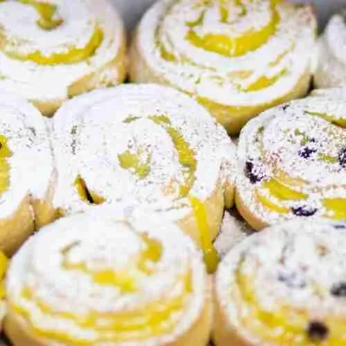 Fertige Vanille-Pudding-Schnecken frisch aus dem Ofen, bestreut mit Puderzucker