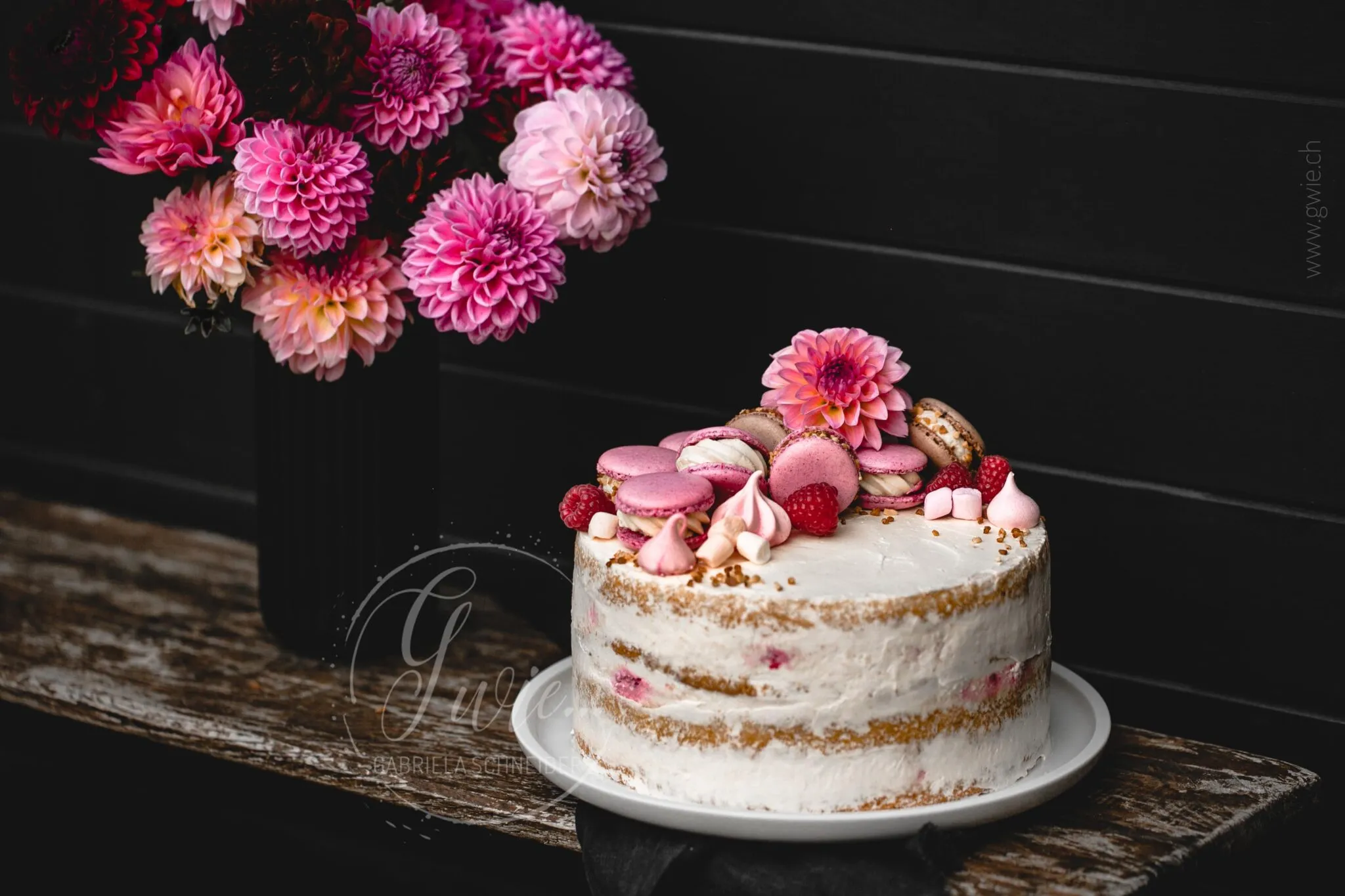 Festliche Torte mit Blumenarrangement vor einem Gartenhaus