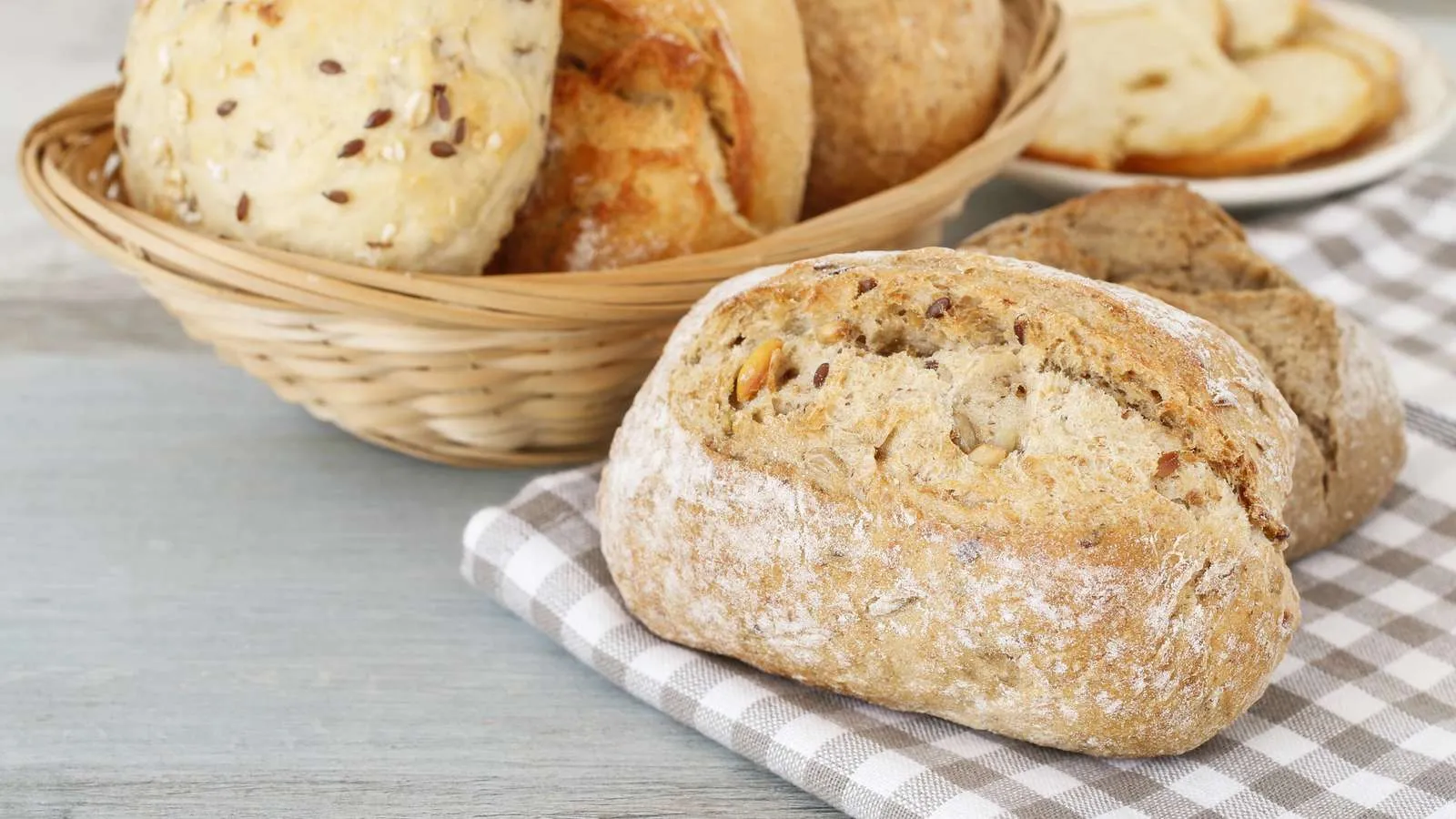 Frisch gebackene Aufbackbrötchen in einem Korb mit Tischtuch