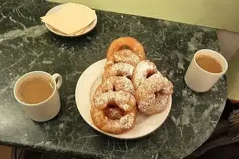 Frisch gebackene Ponchiki (russische Donuts) mit Puderzucker bestreut