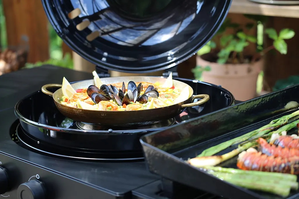 Frisch zubereitete Paella mit Meeresfrüchten und Zitronenspalten auf einer großen Pfanne
