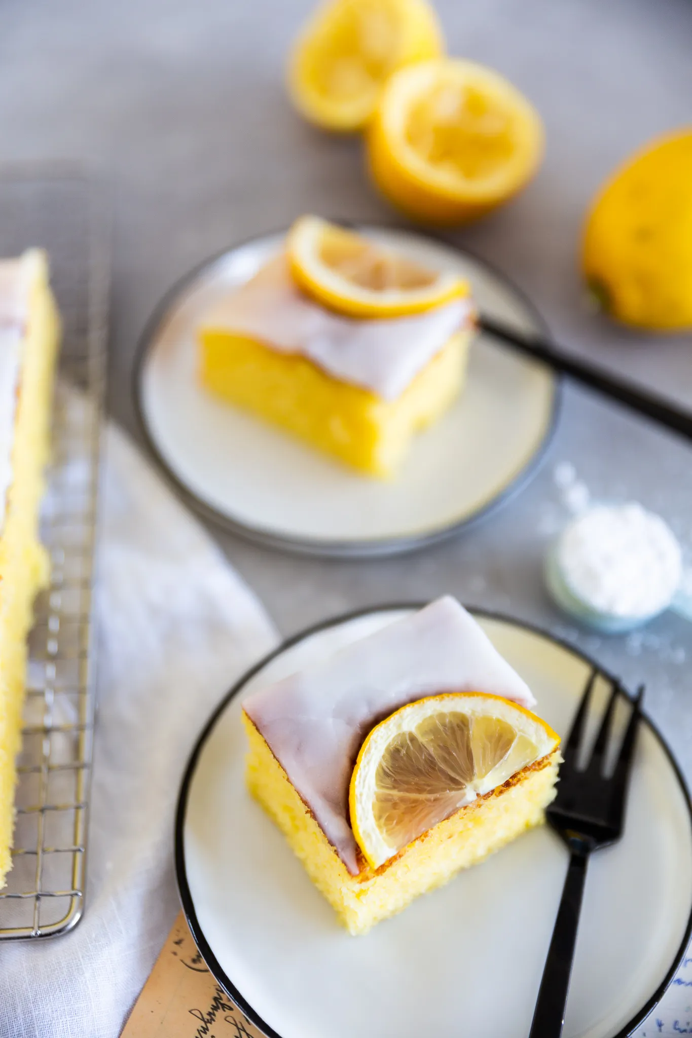 Frisch zubereitete Zitronenglasur auf Puderzucker mit einer ganzen Zitrone im Hintergrund.