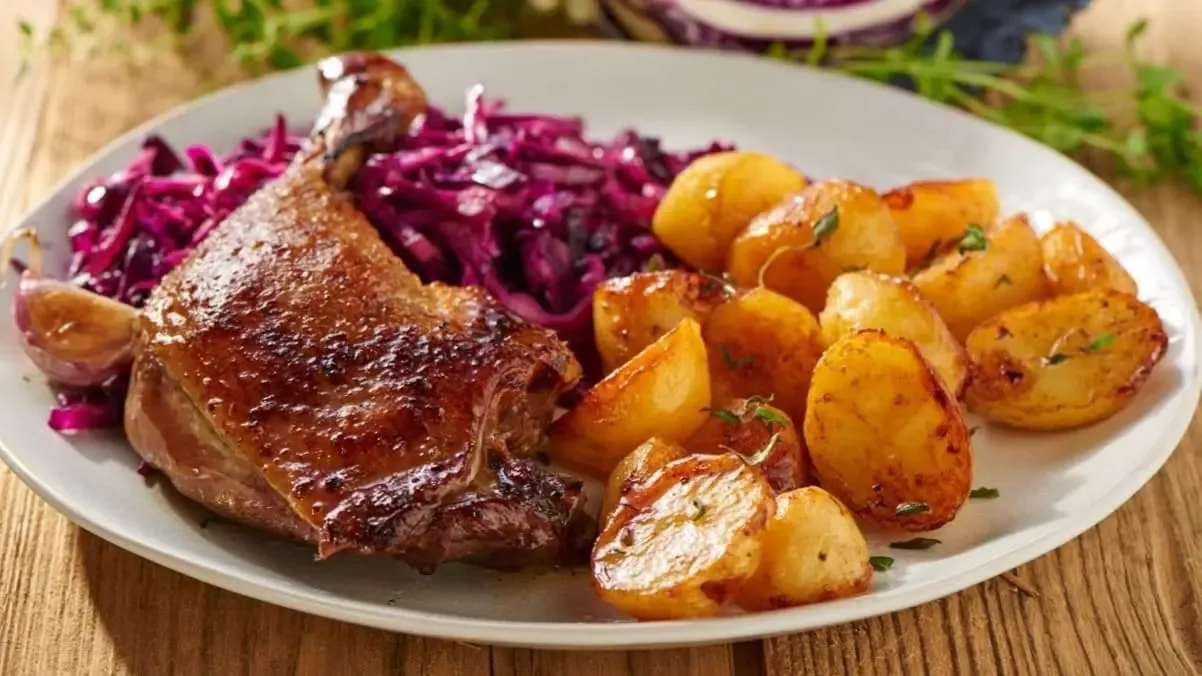 Gänsekeule angerichtet mit knusprigen Kartoffeln und Rotkohl