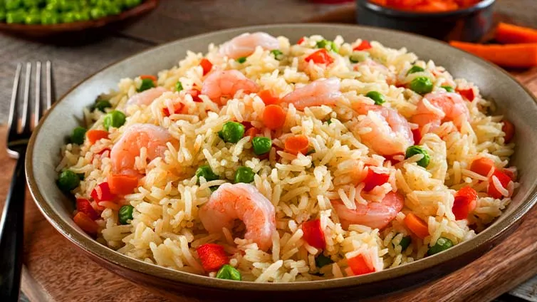 Garnelen Pilaf mit frischem Gemüse appetitlich auf einem Teller angerichtet.