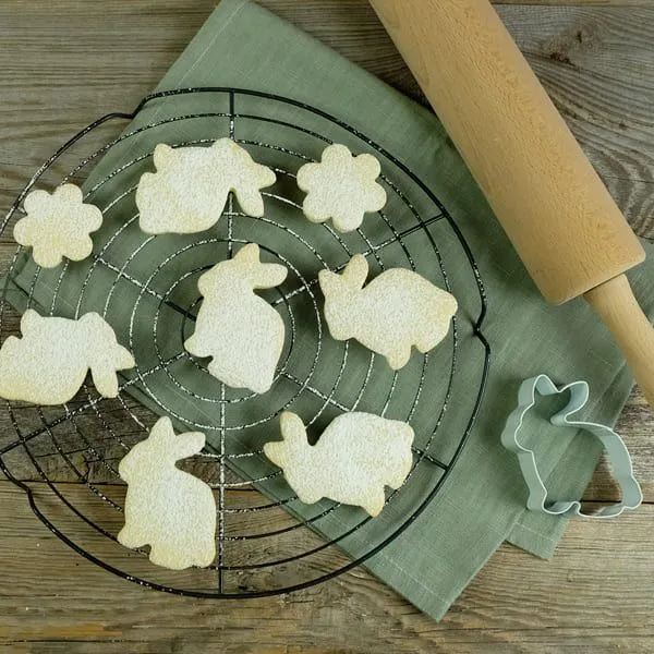Gebackene Osterkekse in Hasen- und Blumenform auf einem Kühlgitter