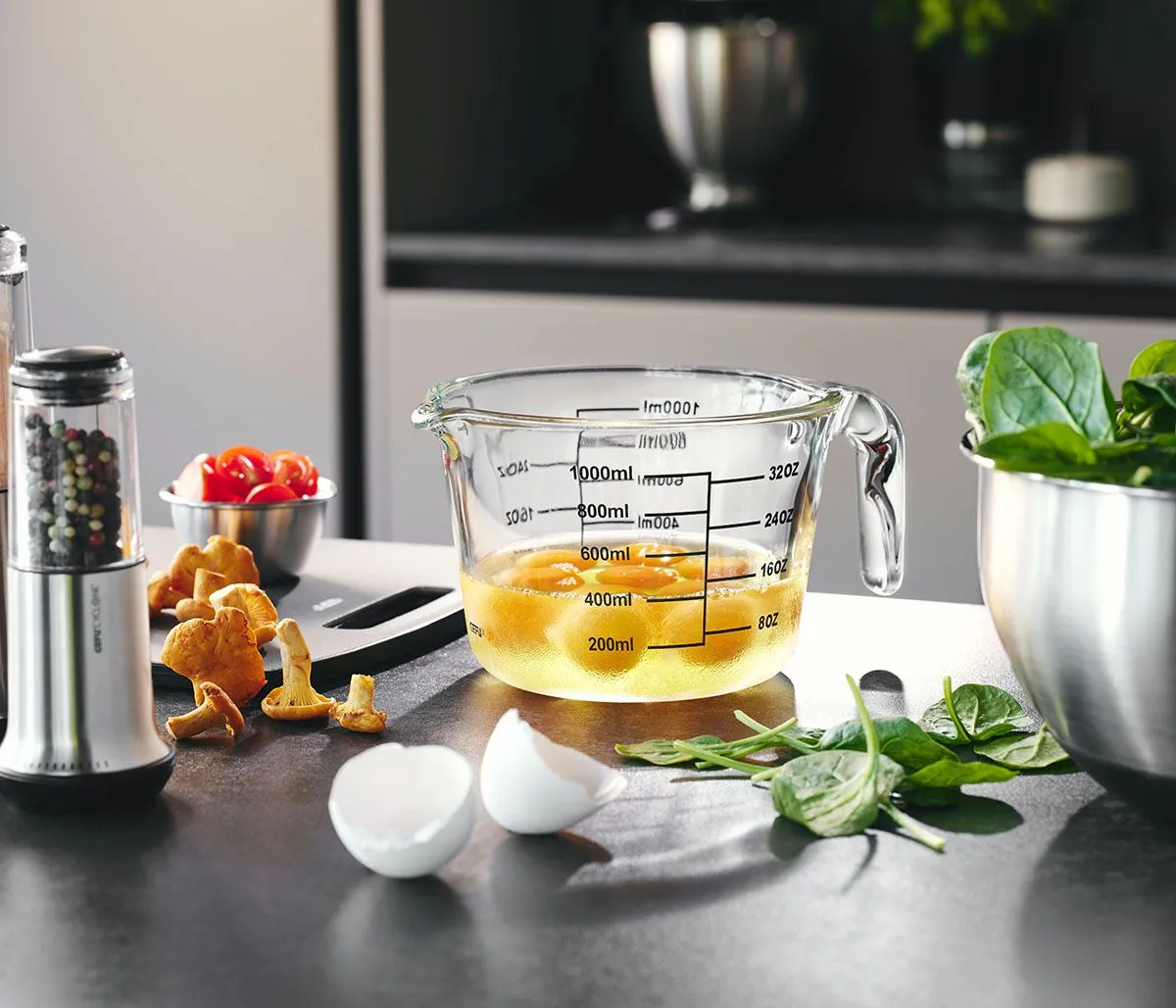 GEFU Glas-Messbecher mit Eiern, umgeben von Pilzen und Spinat auf Küchentheke