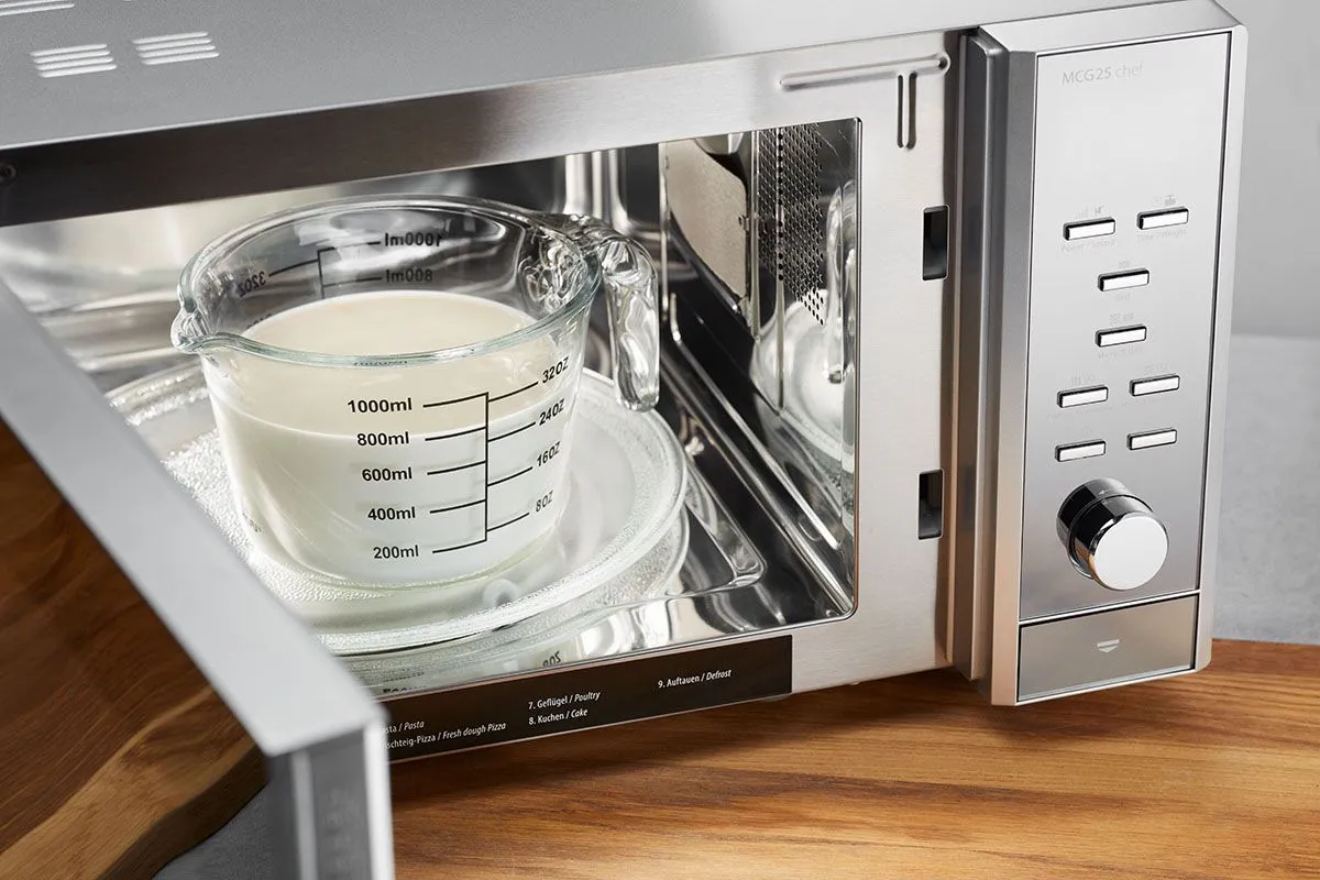 GEFU Glasmesskanne mit Milch auf dem Drehteller einer geöffneten Mikrowelle